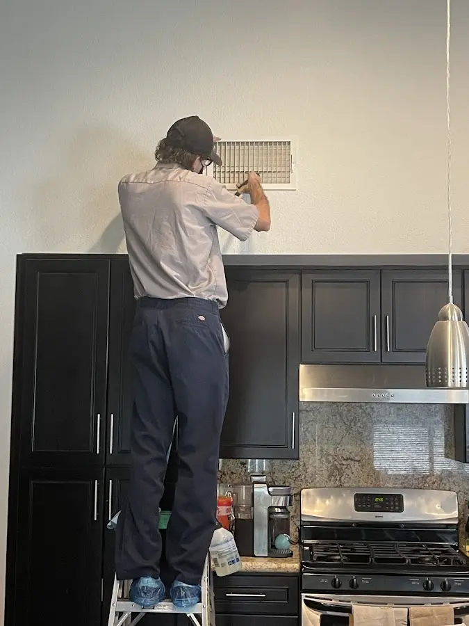 Technician inspecting an air vent during HVAC service in Mineral Wells